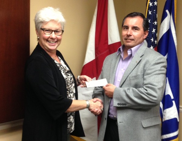 Bruce Shaw, chapter scholarship director, presents a check to Brenda Walker, assistant vice president for development, in June.
